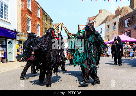 Traditionelle englische Volkstänzer, die Wilde Jagd Morris Dance Seite, in Schwarz tatter Jacken, Tanzen auf der Straße am Sandwich Folk und Ale-Festival. Stockfoto