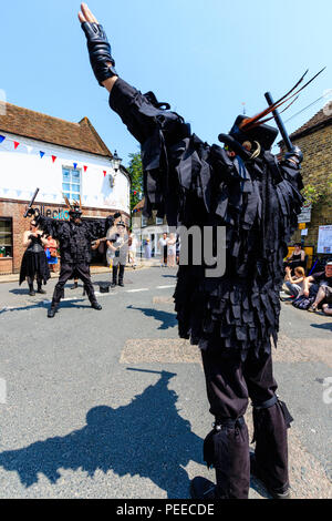 Traditionelle englische Volkstänzer, Wolfs Kopf Morris Dance Seite, in Schwarz tatter Jacken, Tanzen in der Straße am Sandwich Folk und Ale-Festival. Stockfoto