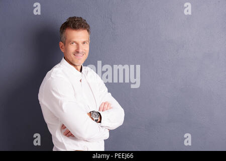 Portrait von Geschäftsmann mittleren Alters tragen Shirt und Kamera, während auf grauen Hintergrund stehen. Stockfoto