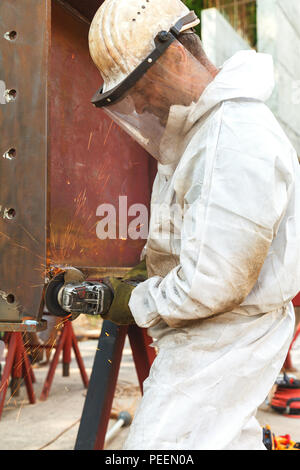 Ein Mitarbeiter in weißen Overalls und eine schützende Maske Prozesse mit elektrischen Flexion einer metallischen Struktur Stockfoto