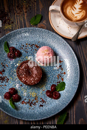 Geschmolzene Schokolade Kuchen (Schokolade Fondant Kuchen/lava Kuchen). Mit Eis, Kirsch Beeren und Tasse Cappuccino serviert. Stockfoto