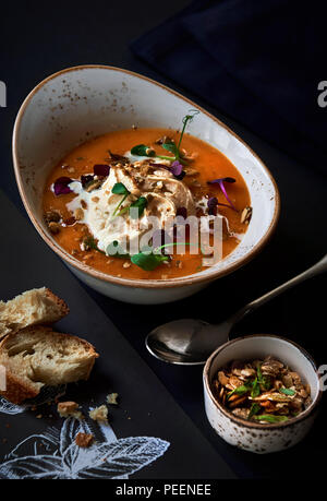 Kürbissuppe, garniert mit Sahne, frische Kräuter und Kürbiskerne Stockfoto