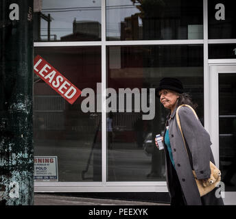 VANCOUVER, BC, Kanada - 11. MAI 2016: Eine Frau geht über einen neu vermieteten Einzelhandelsflächen in Vancouver Downtown Eastside ein Bereich, mit Obdachlosigkeit, Drogenkonsum geplagt wird, und Armut. Stockfoto