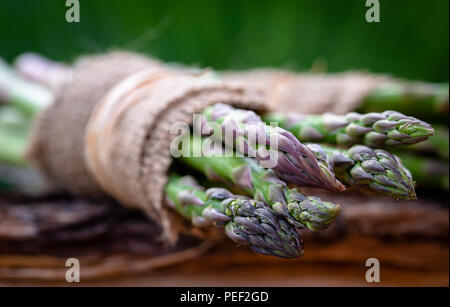 Spargel umwickelt mit Jute auf Holz- Hintergrund. Stockfoto