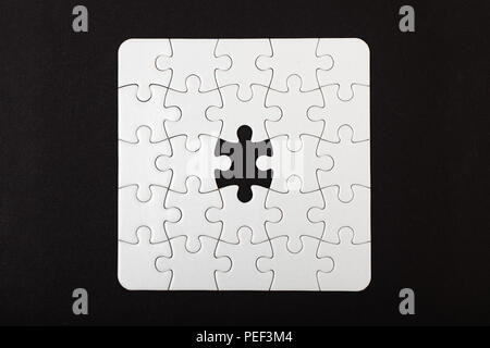 Weiß Puzzle mit einem fehlenden Stück auf schwarzem Hintergrund Stockfoto