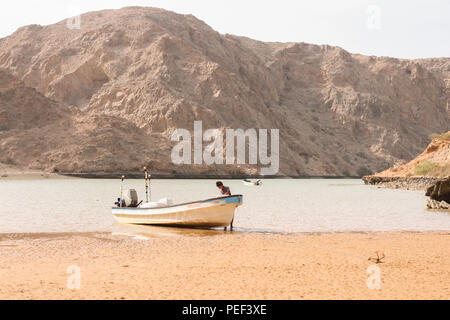 Yiti Muscat Oman Strand an einem sonnigen Tag mit dem trüben Wetter in Bergen im Hintergrund Stockfoto