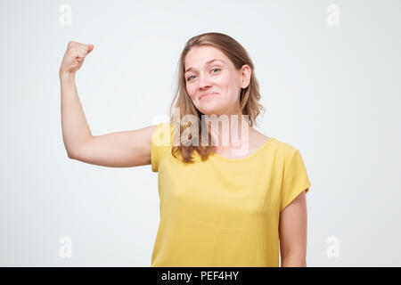 Positive freudige europäischen Frau, hand Muskeln. Kaukasische Frau mittleren Alters in Freizeitkleidung flexing bicep. Stärke oder Feminismus Konzept. Ich bin Stro Stockfoto