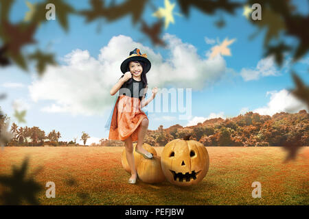 Cute Asian Girl in Hexe Kostüm mit scary pumpkin auf dem autumn park Stockfoto