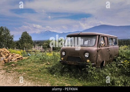 Alten rostigen aufgegeben Minibus im Bergdorf, Haufen Brennholz, Osten Kasachstan Stockfoto