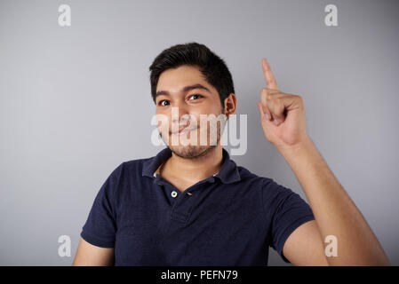 Junger Mann mit Idee Geste auf grauem Hintergrund Stockfoto