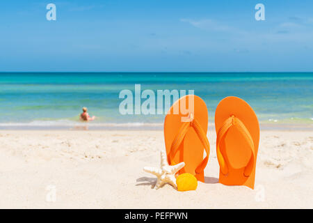 Strand Zubehör einschließlich Flip Flop, Seesterne und Muscheln und Frau, Sandstrand, Meer und blauem Himmel Hintergrund für Sommerurlaub und vacat Stockfoto