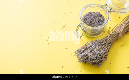 Kräuter Konzept. Ansicht von oben von getrocknetem Lavendel Strauß auf Gelb Tischplatte Hintergrund und im Glas. Stockfoto