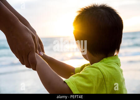 Soft Focus Elternteil, bei dem das Kind Hand bei Sonnenuntergang halten, warmen Ton. Stockfoto