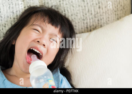 Glücklich süsse kleine Mädchen Trinkwasser aus der Flasche auf dem Sofa zu Hause. health care Konzept. Stockfoto