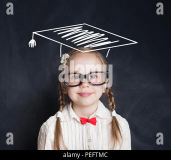 Schule Kind in Gläsern und Graduierung Hut auf Blackboard Hintergrund. Kleines Mädchen Schüler lächelnd Stockfoto