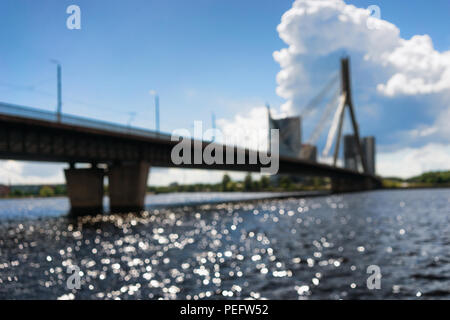 Schrägseilbrücke über den Fluss Daugava in Riga an einem sonnigen Tag mit Reflexionen auf dem Wasser. Verschwommen Stockfoto