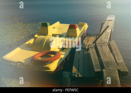 Lettland, Riga - Juli, 2015: Stilisierte mit Blendung licht Foto vintage Tretboot mit einer rettungsleine am alten hölzernen Pier Stockfoto