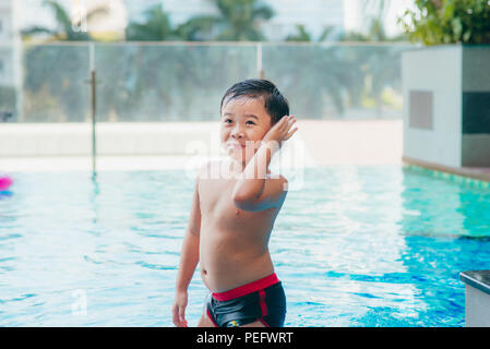 Cute asian kid Reinigung Ohren nach dem Schwimmen in einem Pool Stockfoto