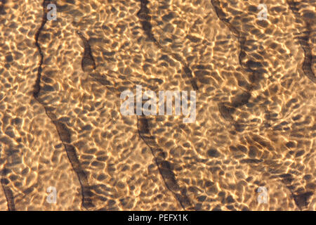 Das Spiel mit dem Licht der Sonne durch die Wellen auf den Sand am Meer Strand der Ostsee Stockfoto