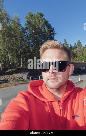 Mitte der erwachsenen Mann in Sonnenbrille einen typischen Stil selfie auf der Straße Stockfoto