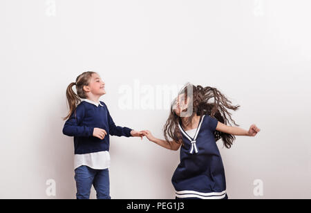 Zwei kleine Mädchen in einem Studio, Hände halten, Spaß haben. Stockfoto