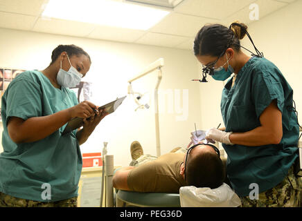 150820-N-SD 120-003 Okinawa, Japan (Aug. 20, 2015) Leutnant Catherine Carlo, rechts, führt eine zahnmedizinische Prüfung auf einen Patienten während Hospital Corpsman 2. Klasse Dominique Jones die Ergebnisse in Naval Mobile Konstruktion Bataillon (NMCB) 5 zahnärztliche Klinik auf Lager Schilde, Okinawa Datensätze. NMCB 5 ist derzeit in Japan und einigen Ländern im Pazifischen Raum von Operationen Durchführung von Bauleistungen und humanitäre Hilfe Projekte bereitgestellt. (U.S. Marine Foto von Mass Communication Specialist 1. Klasse John S. Curtis/Freigegeben) Stockfoto