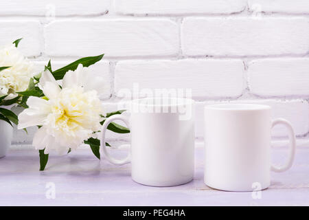 Zwei weiße Kaffeetasse mockup mit hellen Elfenbein Pfingstrose. Leere Becher mock up für Design Promotion. Stockfoto