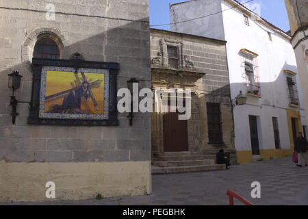 Straßenszene in Jerez de la Frontera, Andalusien, Spanien. Traditionelle alte Gebäude. Eine religiöse Ikone Christi an der Wand. Stockfoto