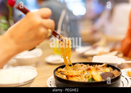 Hand mit Stäbchen Essen japanische Udon Nudeln. Stockfoto