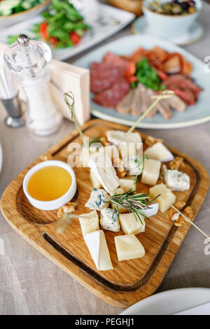 Käseplatte. Käse Mix mit Nüssen, Honig auf Holztisch. Verkostung Teller auf eine Holzplatte. Essen für den Wein. Stockfoto
