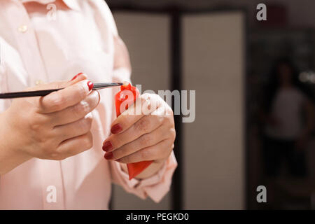 Make-up-Frau Anwendung der Stiftung auf einen Pinsel Stockfoto