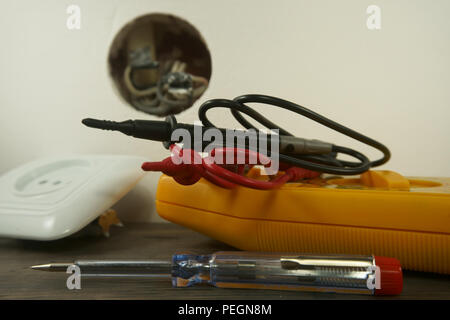 Werkzeuge für die Verkabelung einer elektrischen Steckdose auf dem Boden neben der Kunststoffabdeckung und freien Sockel zeigt interne Schaltkreise Stockfoto