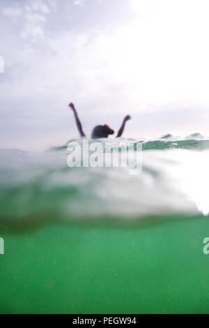 Hände, Arme ist eine 50 Jahre alte Frau und einen Kopf aus dem Meer steigen, das die untere Hälfte des Fotos ist unter dem Meer und Türkis, die obere Hälfte ist Stockfoto