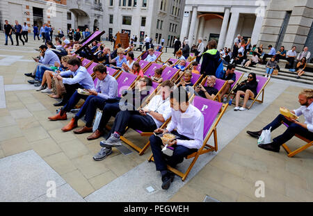 Mitarbeiter im Büro beim Mittagessen sitzen in Liegestühlen, Paternoster Square, London, England Stockfoto