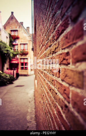 Porträt Blick auf einer der Straßen von Brügge in Belgien, mit einem verschwommenen Mauer im Vordergrund und ein kleines Restaurant in der Rückseite Stockfoto