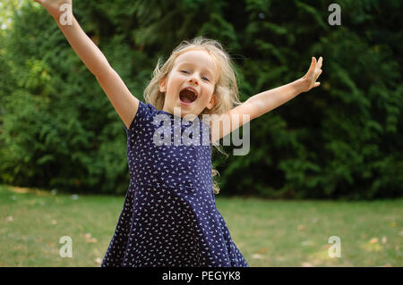 Lustige überrascht kleine blonde Mädchen, das schreiend in den Park. Im freien Portrait von Happy Interaktive weiblichen Kind. Stockfoto