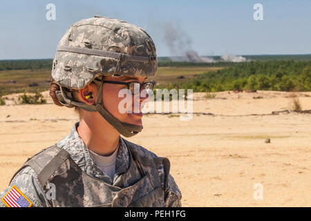 2. Lt. Jennifer Wain, 3-112 th Field Artillery, New Jersey Army National Guard, posiert für ein Portrait als 155 mm Runde aus einer M 777 A2 leichte Haubitze detoniert, die im Hintergrund während einer Live Fire Übung in Joint Base Mc Guire-Dix - Lakehurst, New Jersey, 26.08.2015. Wain, ein Feuer Richtung Offizier mit der 3-112., ist die erste weibliche Combat Arms Officer in der Geschichte der New Jersey Army National Guard. (U.S. Air National Guard Foto von Master Sgt. Mark C. Olsen/Freigegeben) Stockfoto