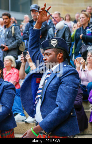 Glasgow, UK. 15. Aug 2018. Straßentheater in der Buchanan Street, Glasgow mit mehr internationale Pipe Bands spielen in der Nähe der Donald Dewar Statue die Öffentlichkeit für sich zu unterhalten. Die Pipe Band Championships schließen am Samstag, den 18. August auf Glasgow Green. Foto von Owen RUSSELL aus den USA spielen mit dem Simon Frase University Pipe Band aus British Columbia, Kanada Kredit: Findlay/Alamy leben Nachrichten Stockfoto