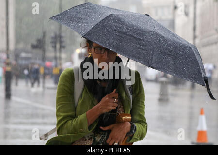 Trafalgar Square. London. 16 Aug 2018 - Touristen Schutz vor dem Regen unter Sonnenschirmen bei starken Niederschlägen in der Hauptstadt. Credit: Dinendra Haria/Alamy leben Nachrichten Stockfoto