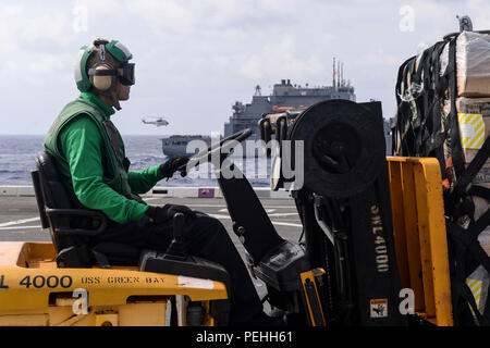 150821-N-TW 634-061 philippinischen Meer (Aug. 21, 2015) Aviation Support Equipment Techniker 3. Klasse Ziyun Tian, von Peking, China, verwendet ein Gabelstapler für den Transport über die Flight Deck des amphibious Transport dock Schiff USS Green Bay LPD (20) als das Schiff eine vertikale Auffüllung führt mit dem Dry Cargo und Munition ship USNS Matthew Perry (T-AKE 9). Green Bay ist auf die Bonhomme Richard Expeditionary Strike Group zugeordnet und wird auf Patrouille in den USA 7 Flotte Bereich der Operationen. (U.S. Marine Foto von Mass Communication Specialist 3. Klasse Derek A. Harkins/Freigegeben) Stockfoto