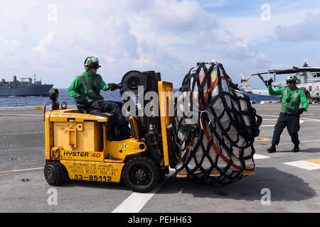 150821-N-TW 634-147 philippinischen Meer (Aug. 21, 2015) Aviation Support Equipment Techniker 2. Klasse Lloyd Fierro, rechts, von Pico Rivera, Calif., leitet Aviation Support Equipment Techniker 3. Klasse Ziyun Tian, links, von Peking, China, wie er einen Gabelstapler verwendet für den Transport über die Flight Deck des amphibious Transport dock Schiff USS Green Bay (LPD 20) während einer vertikalen Auffüllung mit dem Dry Cargo und Munition ship USNS Matthew Perry (T-AKE 9). Green Bay ist auf die Bonhomme Richard Expeditionary Strike Group zugeordnet und wird auf Patrouille in den USA 7 Flotte Bereich der Operationen. Stockfoto