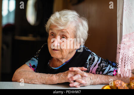 Eine ältere Frau am Tisch. Stockfoto