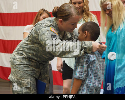 New York Army National Guard Staff Sgt. Marlana Watson präsentiert ihre New York Staatsmedaille für Valor, höchste militärische Ehre des Staates, zu ihrem Sohn Lassan Grün, 6, 12.08.19, 2015, nach größeren General Patrick Murphy, der Adjutant General von New York, um ihr in die Farmingdale, New York, Streitkräfte Mitte vorgestellt. Watson war für ihre Tätigkeiten auf, Nov. 5, 2015, als sie aus ihrem Haus geeilt medizinische Behandlung zu zwei Opfer eines Drive zu bieten - durch das Schießen geehrt, obwohl sie nicht wissen, ob oder nicht der Shooter würde weiter Feuer. (U.S. Army National Guard Foto von Sgt. J.P. Lawrenc Stockfoto