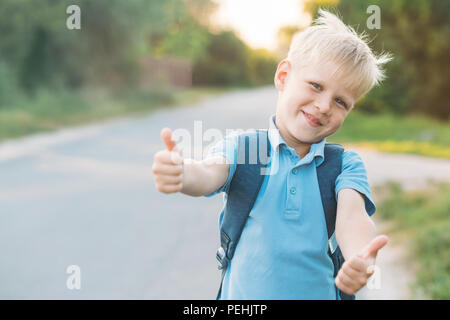 Fröhliche Junge bleiben auf der Seitenlinie und gibt mit dem Daumen nach oben. Schüler mag Bildung. Stockfoto