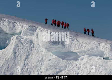 Touristen wandern auf einem verschneiten Hügel in der Antarktis Stockfoto