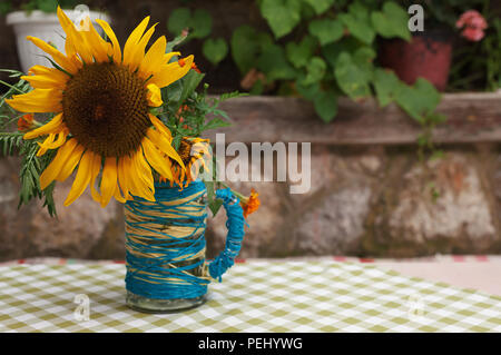 Details zu lebhaft gelben Sonnenblumen in Keramik Schale auf alten heimischen Tisch. Stockfoto