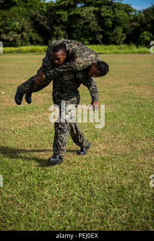 Einen Honduranischen marine Feuerwehrmann trägt eine andere Marine während des Manövers unter Feuer Teil der Bekämpfung der Fitness Test am Marinestützpunkt Puerto Castilla, Honduras, 12.08.2015. Us-Marines mit Sicherheit Zusammenarbeit Team-Honduras, Special Purpose Marine Air-Ground Task Force-Southern Befehl das Ereignis überwacht. SCT-Honduras ist derzeit als Teil der SPMAGTF-SC bereitgestellt werden, um das Centro de Adiestramiento Naval mit der Umsetzung eines Lehrplans einen Honduranischen marine Programm zu schaffen, zu unterstützen. (U.S. Marine Corps Foto von Cpl. Katelyn Hunter/Freigegeben). Stockfoto