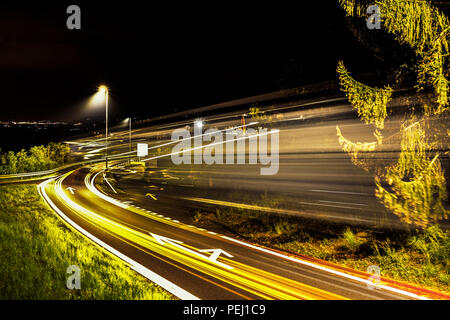 Lange Belichtung geschossen von einer Ausfahrt der Autobahn in der Nähe der Stadt Fribourg in der Schweiz, mit Bäumen und öffentliche Beleuchtung im Hintergrund Stockfoto