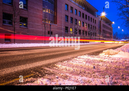 Lange Belichtung geschossen von den Straßen von Fribourg in der Schweiz, mit Schnee auf der Straße, Fahrzeug leichte Wanderwege und eine Universität im Hintergrund Stockfoto