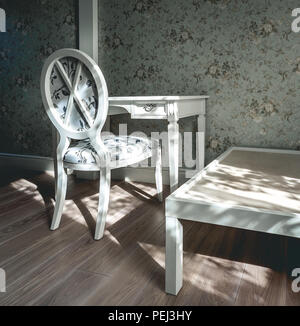 Vintage Zimmer mit Sessel, Tisch und geblümten Tapeten. Weiß und hell türkis Stockfoto